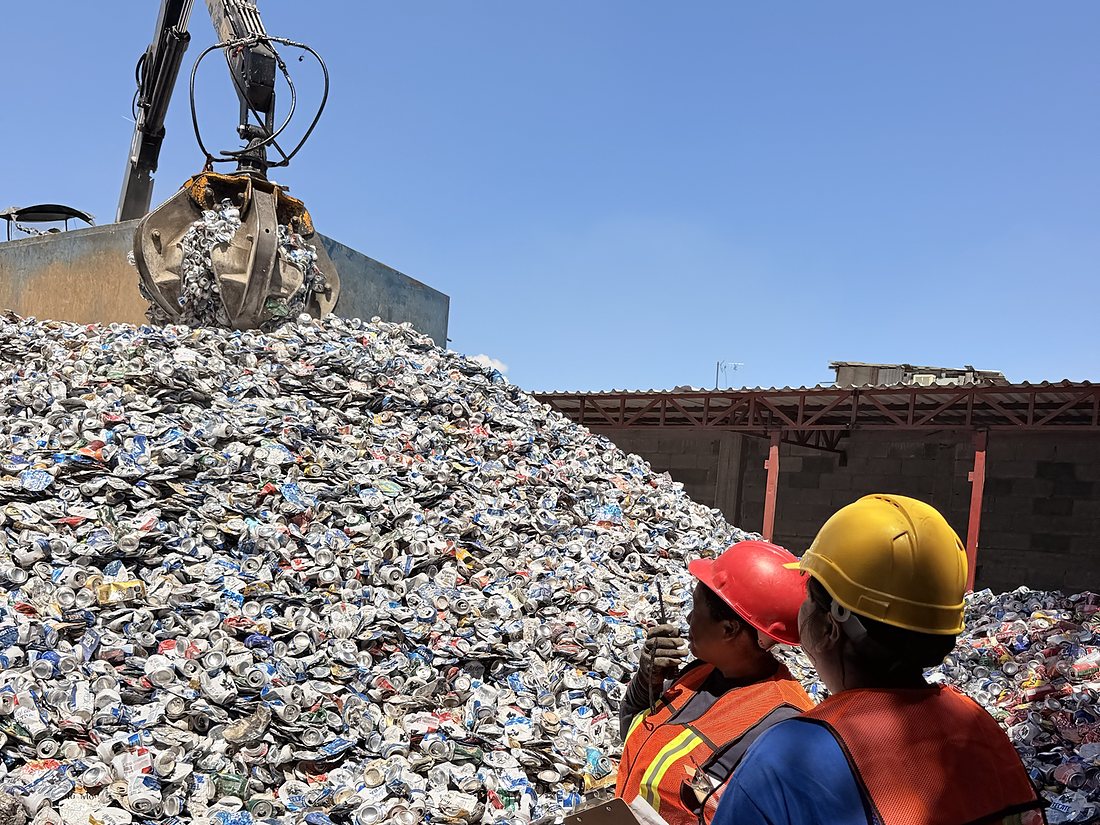 Grúa descargando bote de aluminio mientras dos supervisoras con equipo de seguridad registran el material